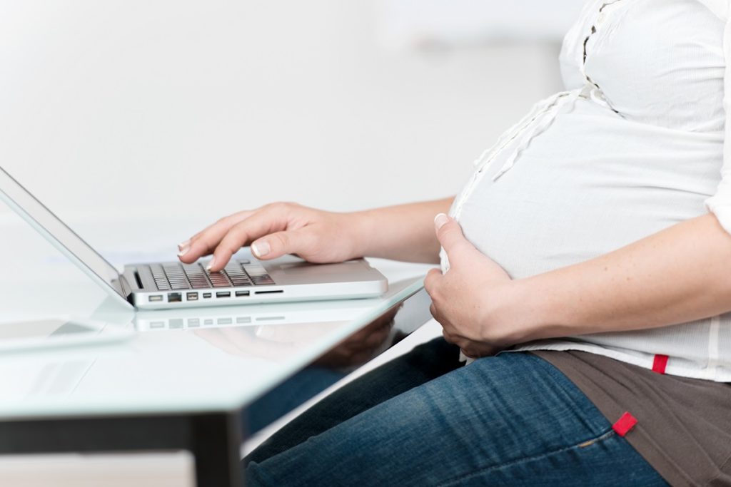 gravidanza2-1024×683 21246714 - midsection of pregnant woman with hand on belly using laptop at table in house