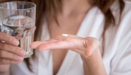 Woman holding pill and glass of water, close up view Woman holding pill and glass of water in hands taking emergency medicine, supplements or antibiotic antidepressant painkiller medication to relieve pain, meds side effects concept, close up view