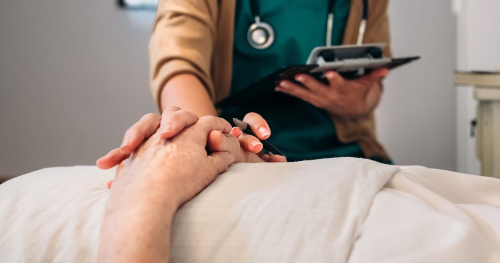 Female doctor comforting older patient Unrecognizable young female doctor comforting unrecognizable older female patient
