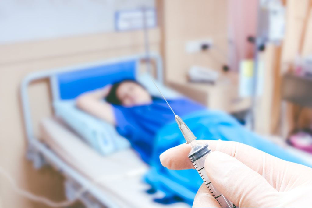 Medical syringe in the doctor's hands on the patient's in room hospital blur background