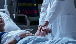 Close-up of a doctor checking pulse of his dying of cancer patient in the hospital